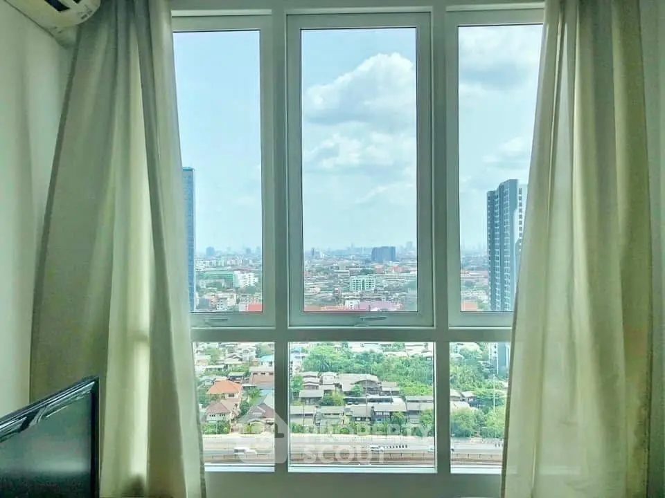Stunning city view from a high-rise apartment window with bright natural light.