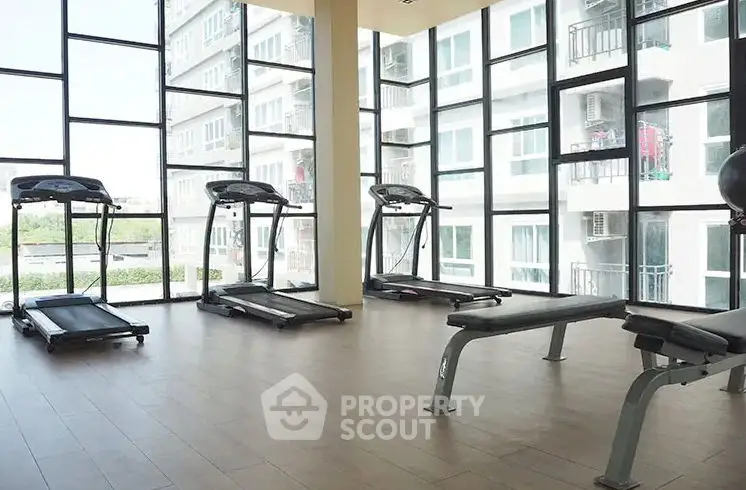 Modern gym with treadmills and large windows in a residential building