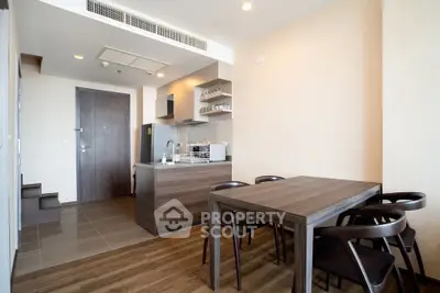Modern open-layout kitchen and dining area with wooden furniture and sleek design.
