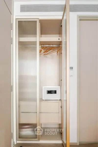 Modern apartment closet with built-in safe and wooden hangers