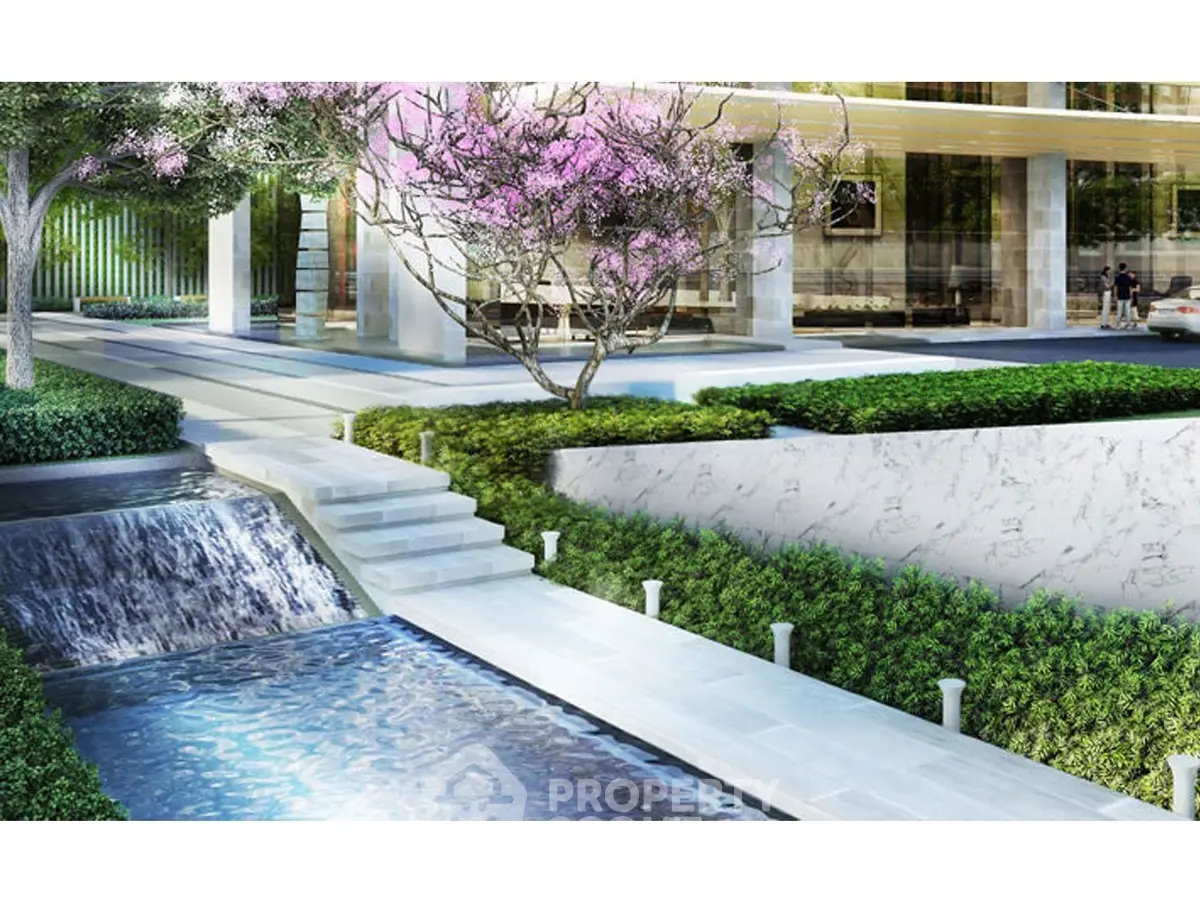 Luxurious modern building entrance with water feature and lush landscaping