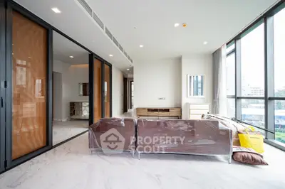 Spacious modern living room with large windows and sleek furniture in a luxury apartment.
