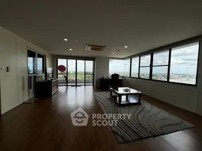 Spacious living room with panoramic city views and modern furnishings.
