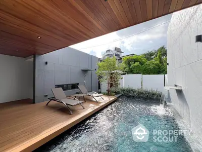 Luxurious modern poolside area with wooden deck and sun loungers