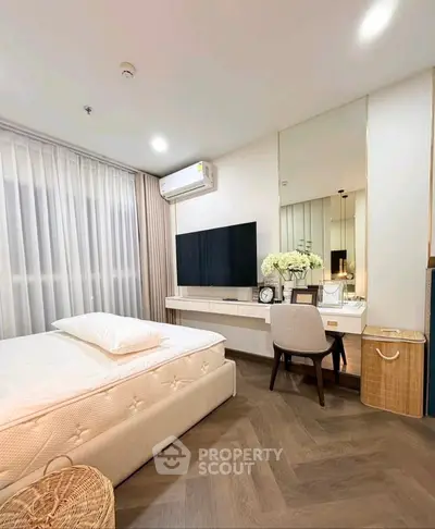 Elegant bedroom with modern decor, featuring a large TV, stylish vanity, and cozy bed in a bright, airy space.