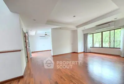 Spacious empty living room with wooden flooring and large windows