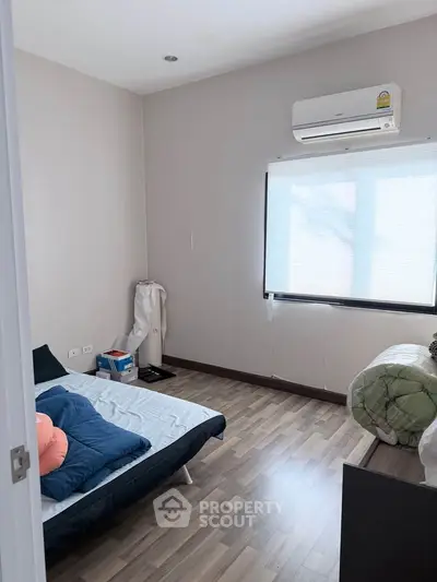 Cozy bedroom with wooden flooring and air conditioning, perfect for relaxation.