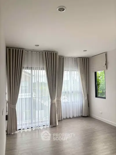 Bright empty room with large windows and elegant curtains, perfect for customization.
