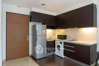 Modern kitchen with sleek cabinetry, stainless steel fridge, and built-in washing machine.