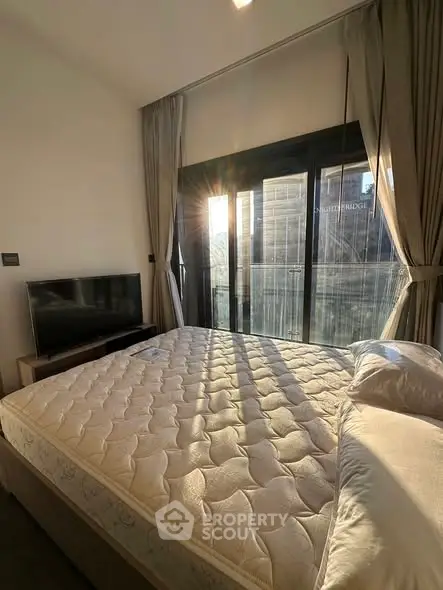 Bright bedroom with large window and modern furnishings, showcasing a cozy and inviting atmosphere.