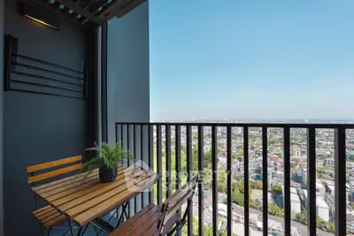 Stunning high-rise balcony with panoramic city views and cozy seating area.