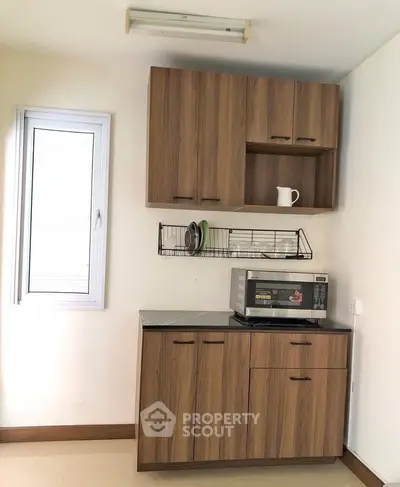 Modern kitchen with wooden cabinets and microwave, perfect for compact living spaces.