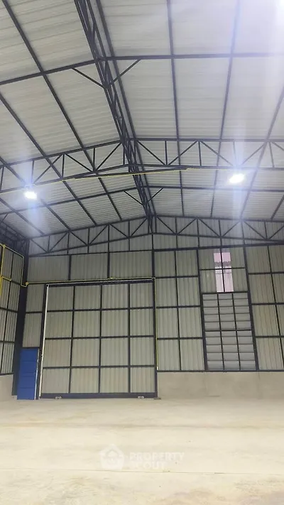 Spacious industrial warehouse with high ceilings and metal framework, ideal for storage or manufacturing.