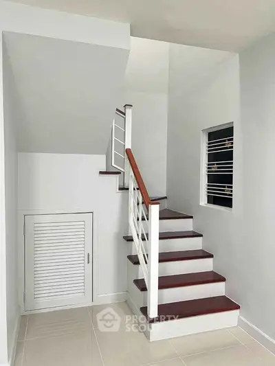 Modern staircase with sleek white and wood finish in a bright interior space.