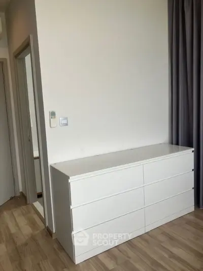 Modern minimalist bedroom with white dresser and wooden flooring