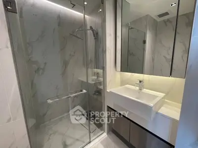 Modern bathroom with glass shower and sleek vanity in luxury apartment.