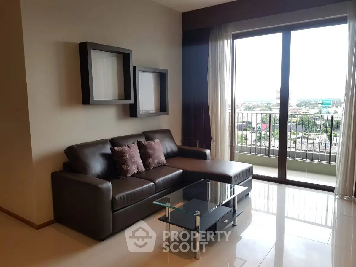 Modern living room with sleek leather sofa and glass coffee table, featuring a balcony with city view.