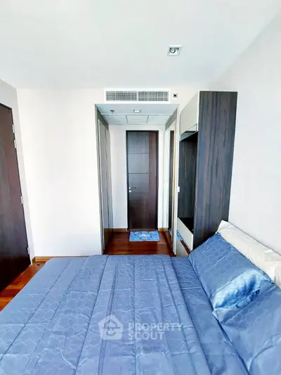 Modern bedroom with sleek design and blue bedding in a high-rise apartment.