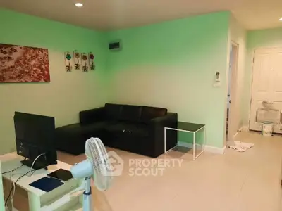 Spacious living room with modern black sofa and wall art, ideal for relaxation and entertainment.