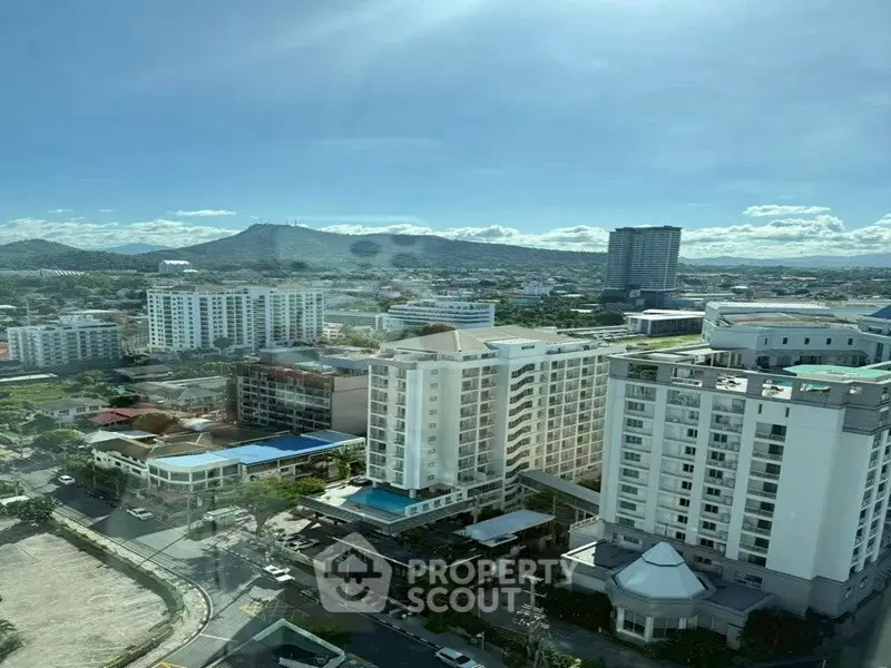 Stunning cityscape view from high-rise building with mountains in the background, perfect for urban living.