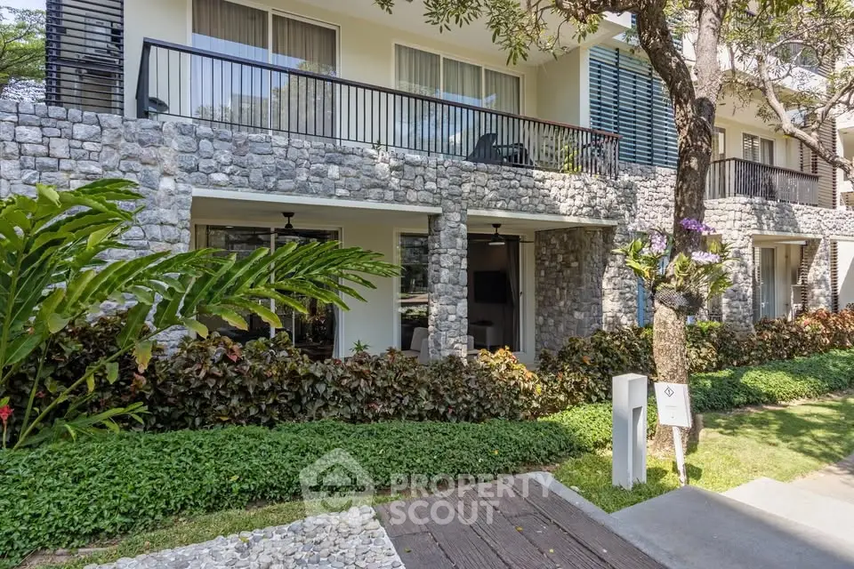 Charming stone facade building with lush greenery and private balconies, perfect for serene living.