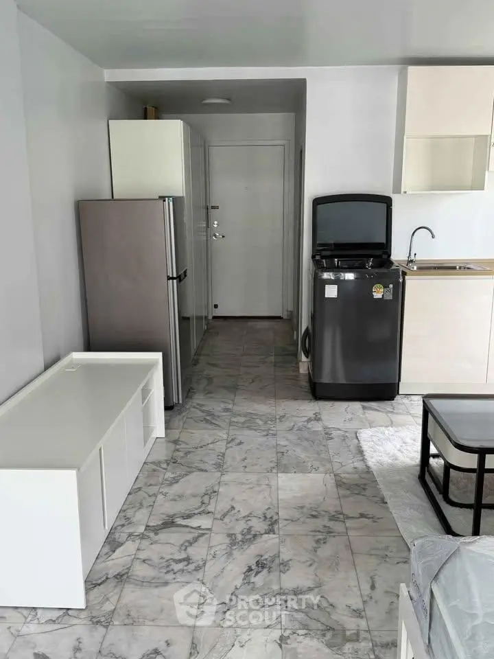 Modern compact kitchen with sleek appliances and marble flooring in a cozy apartment.