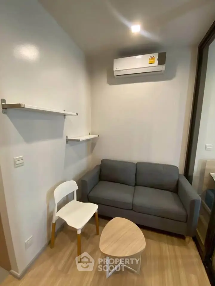 Cozy living room with modern sofa, chair, and air conditioning, perfect for relaxation.