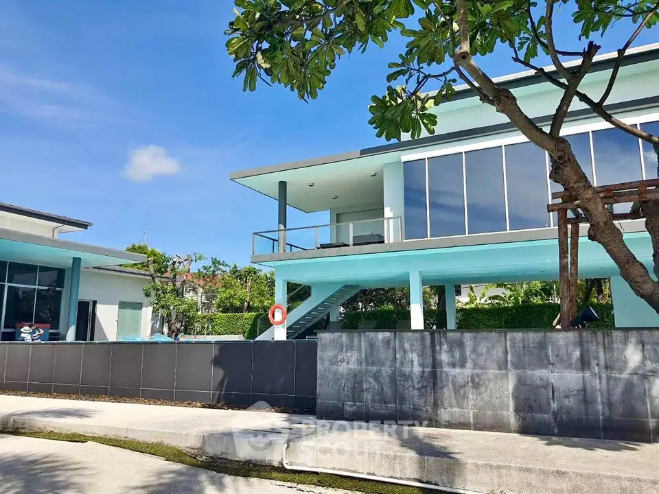 Modern two-story house with large windows and lush greenery, perfect for luxury living.