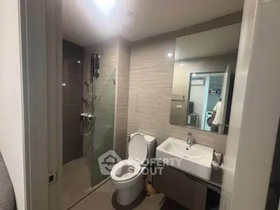 Modern bathroom with glass shower and sleek fixtures in contemporary apartment.