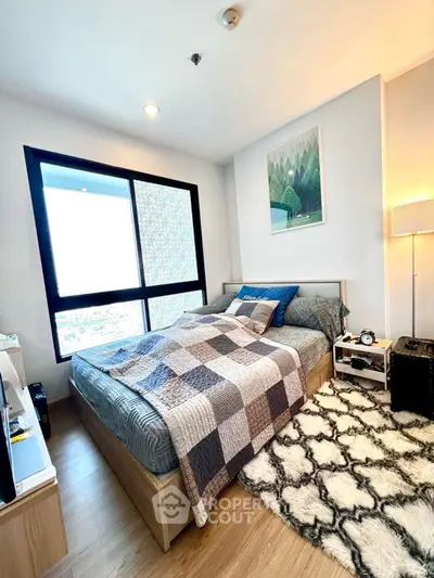 Cozy bedroom with modern decor and large window offering natural light.