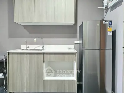 Modern kitchen with sleek cabinetry and stainless steel fridge in a compact layout.