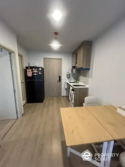 Modern kitchen with wooden flooring, compact dining area, and integrated appliances.