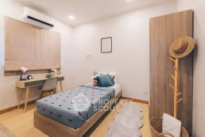 Cozy bedroom with modern decor, featuring a single bed, study desk, and stylish wooden accents.