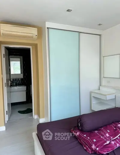 Cozy bedroom with sliding closet doors and ensuite bathroom in modern apartment.