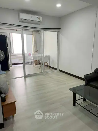 Spacious living room with modern glass doors and sleek flooring, perfect for contemporary living.