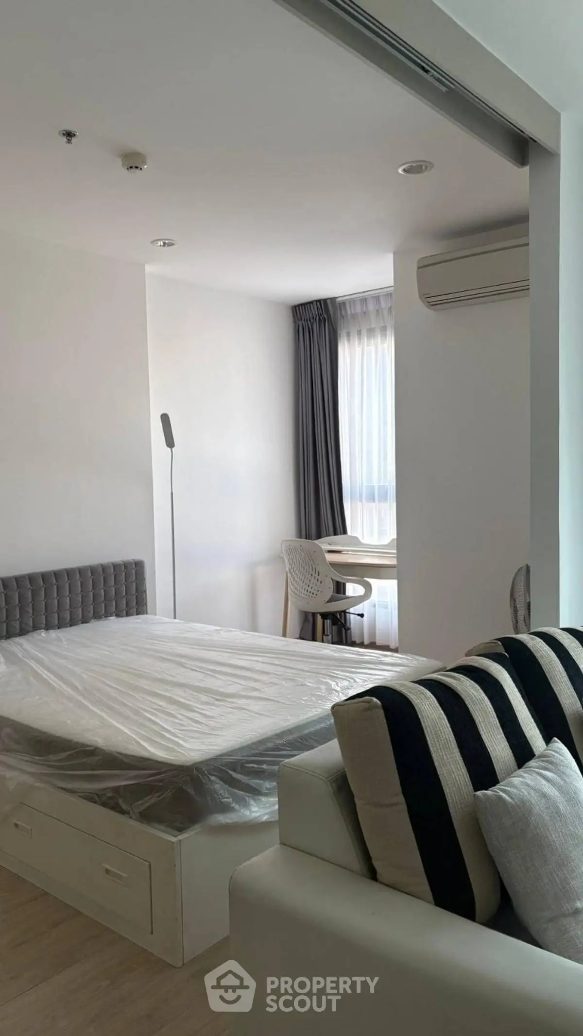 Modern bedroom with stylish decor and natural light, featuring a cozy bed and workspace.