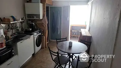 Cozy kitchen with gas stove, oven, and washing machine, complemented by a dining area with a round table and chairs, offering a practical and inviting space.