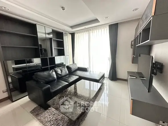 Modern living room with sleek black leather sofa and large windows for natural light.