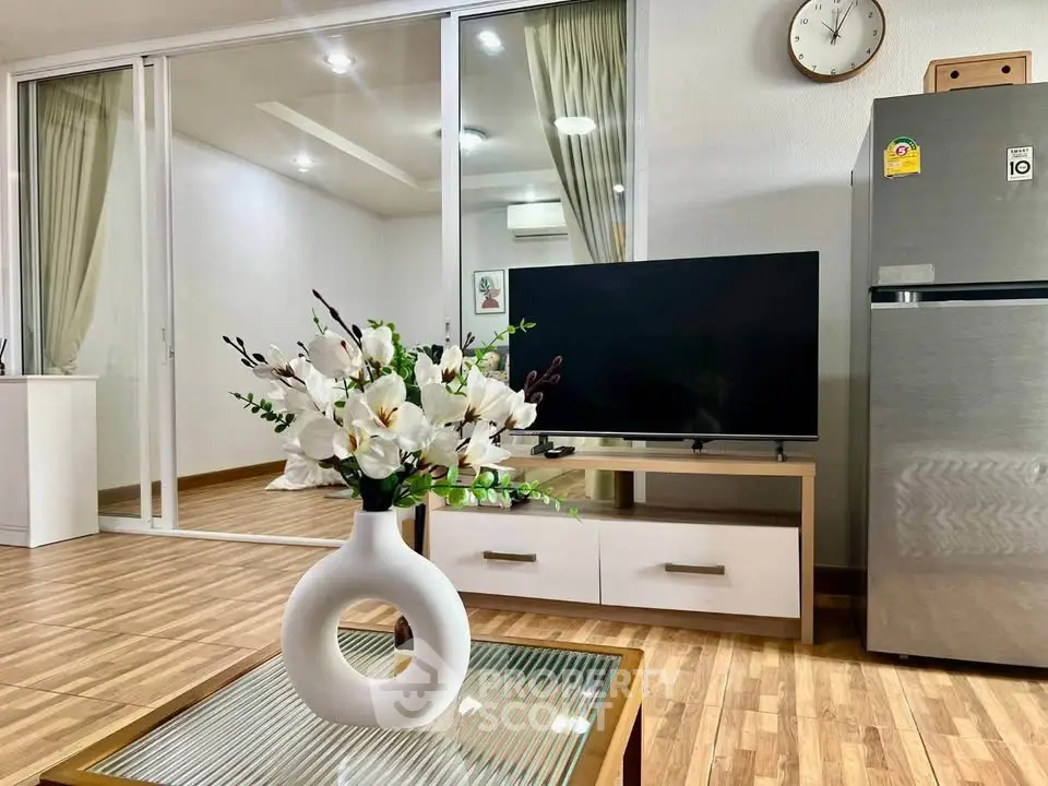 Modern living room with sleek TV, stylish decor, and elegant flooring in a contemporary apartment.