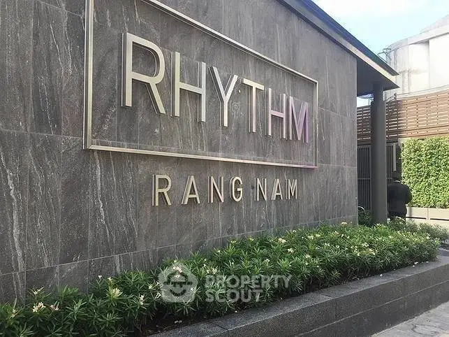 Modern building exterior with stylish signage and lush greenery at Rhythm Rangnam.
