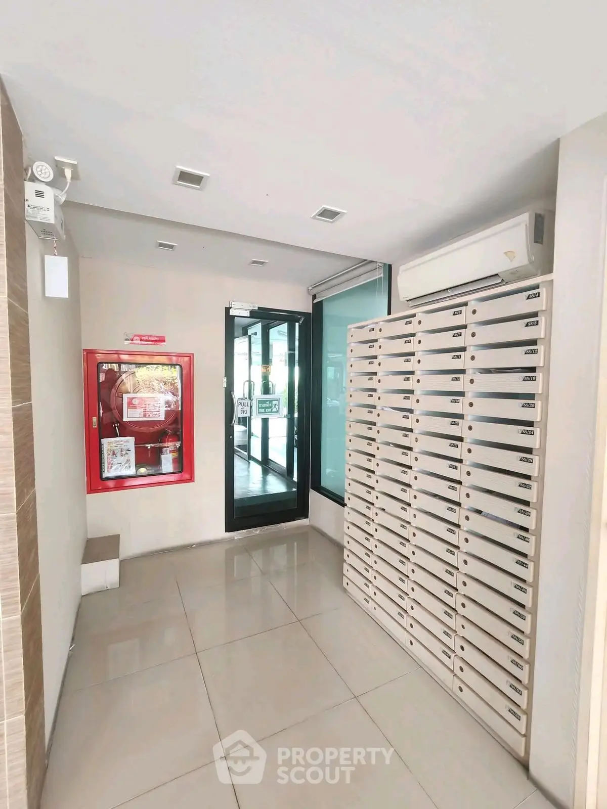 Modern apartment building entrance with mailboxes and fire safety equipment.