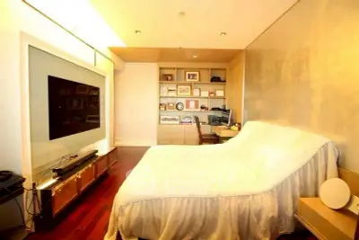Spacious bedroom with modern TV setup and cozy bed in elegant apartment.