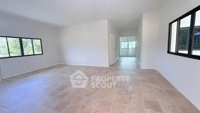 Spacious empty living room with large windows and tiled flooring, ready for customization.