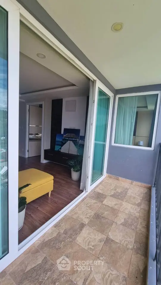 Spacious balcony with sliding glass doors opening to a modern living room, perfect for relaxation.