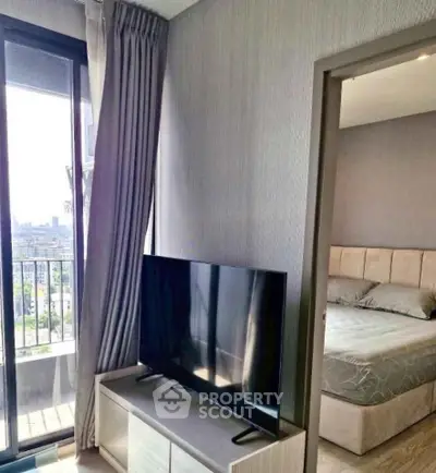 Modern bedroom with balcony access and city view, featuring a sleek TV setup.
