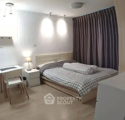 Cozy bedroom with modern decor and natural lighting, featuring a comfortable bed and study area.
