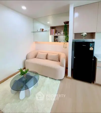 Chic modern living room with cozy sofa, glass coffee table, and sleek kitchen area.