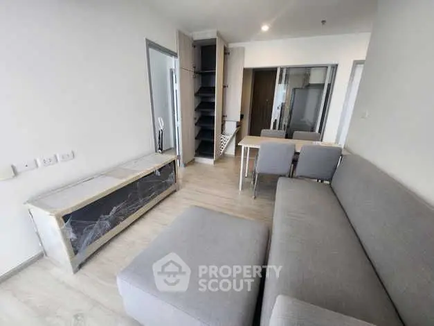Modern living room with gray sofa and open shelving in a minimalist apartment.