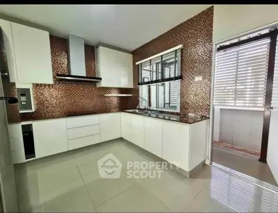Modern kitchen with sleek design and mosaic backsplash, featuring open layout and ample natural light.