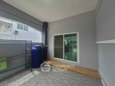 Spacious outdoor area with tiled flooring and sliding glass door, perfect for relaxation or storage.